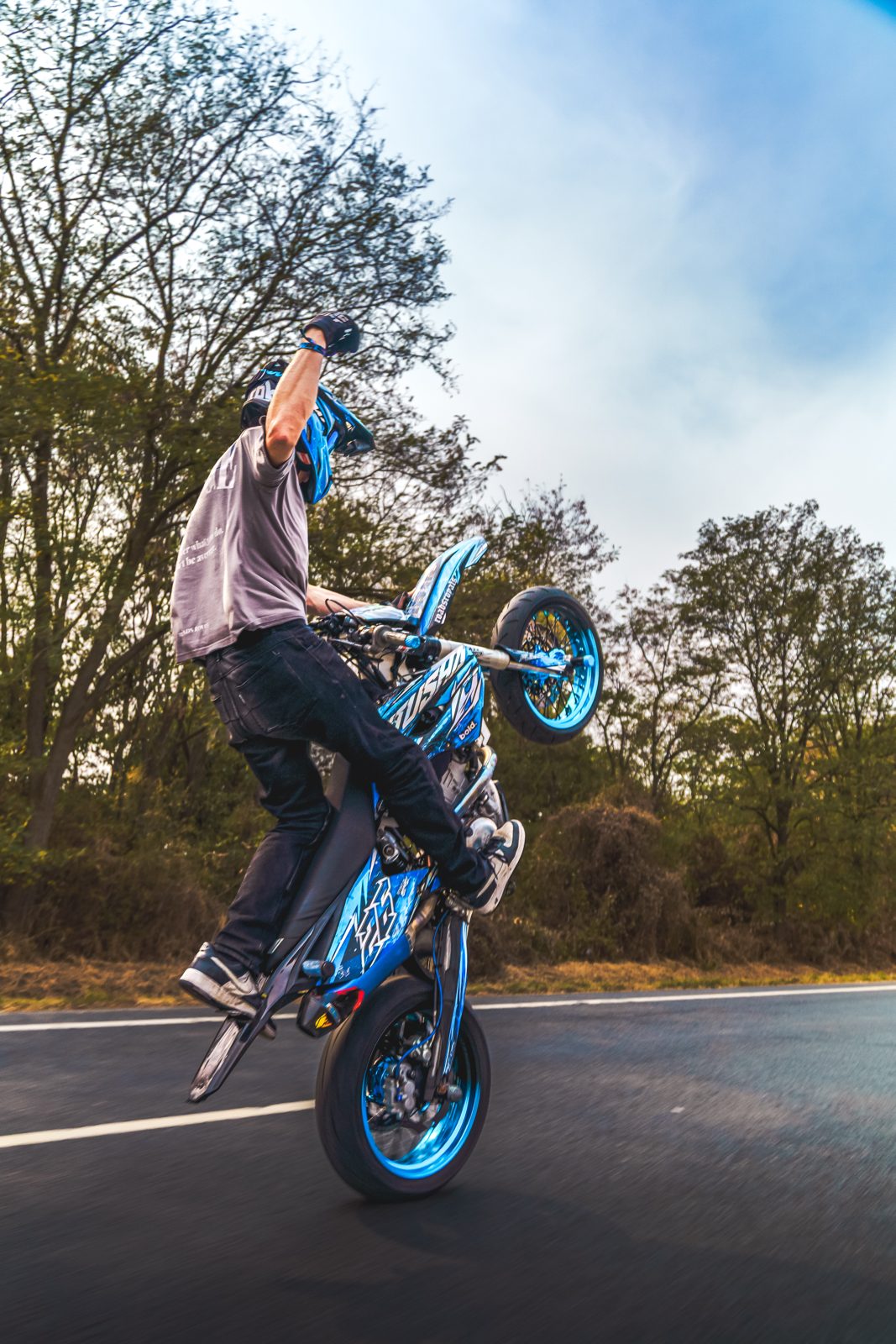 Stehend auf dem Bike mit erhobener Faust im Wheelie